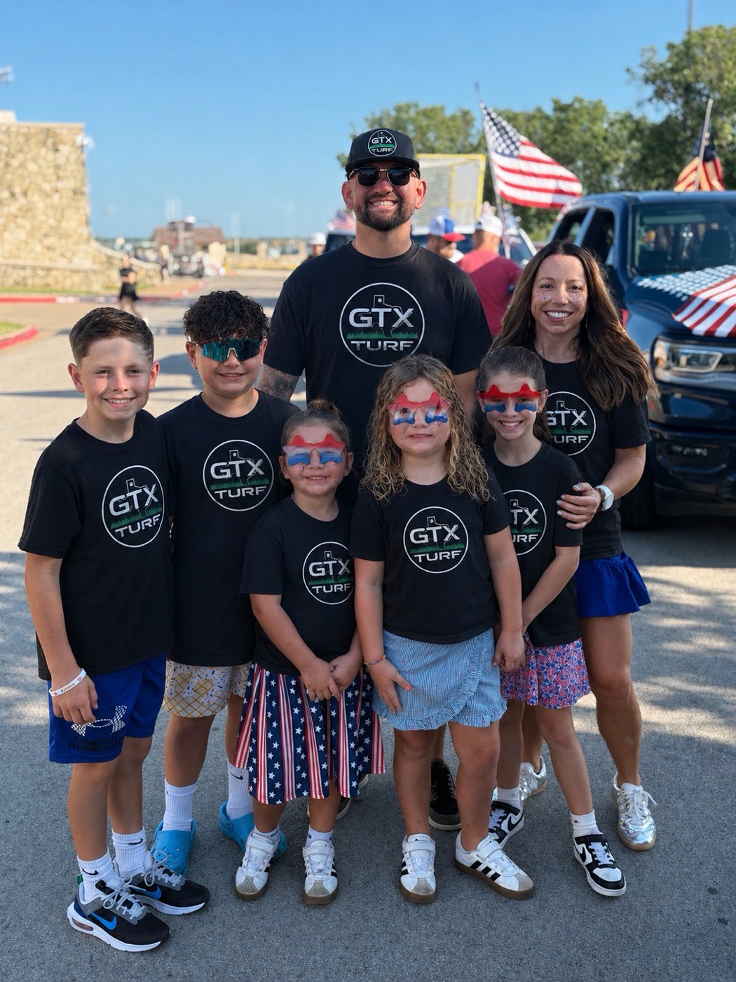 Mathew Lewis with his family, all wearing GTX Turf shirts at a Fourth of July parade
