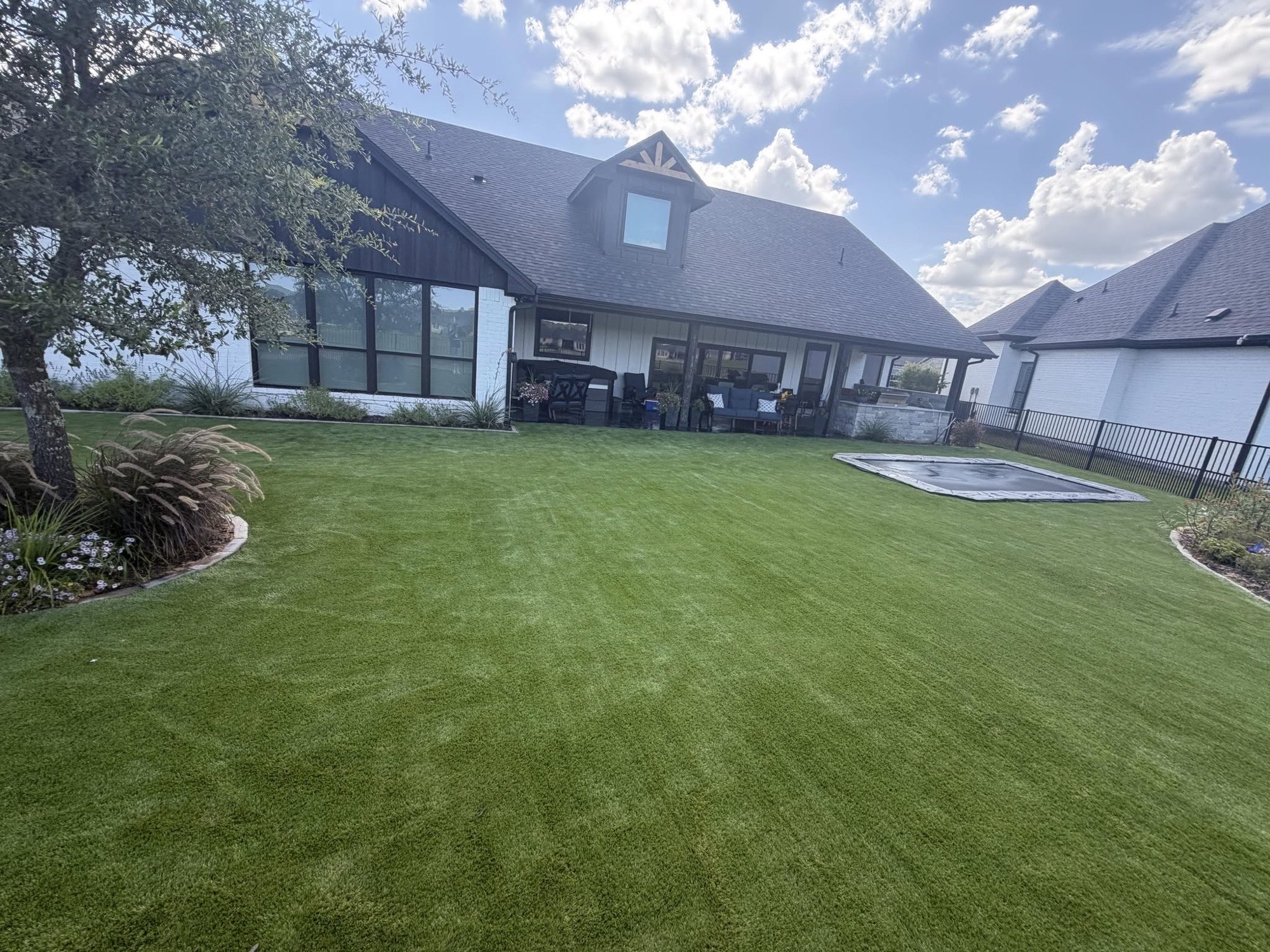 Large residential backyard with freshly installed artificial turf in Texas