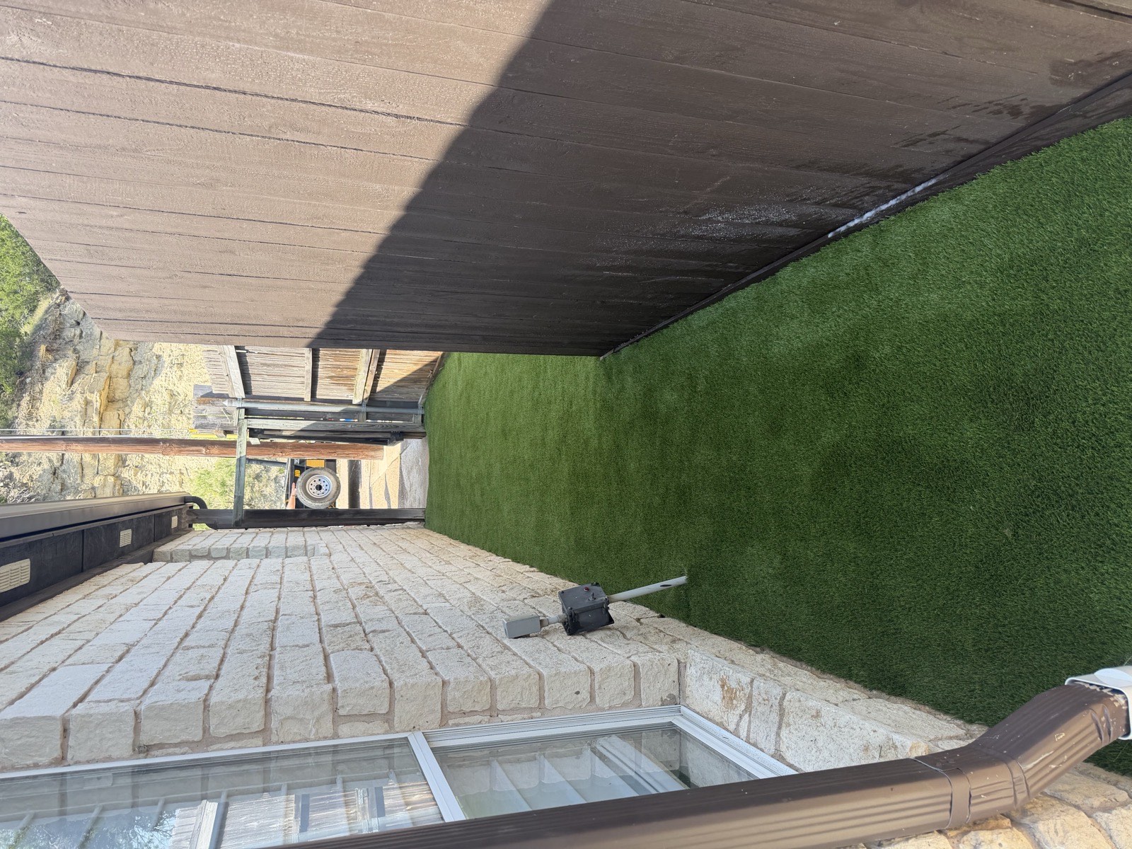 Wide artificial turf lawn with a shade tree and flower beds