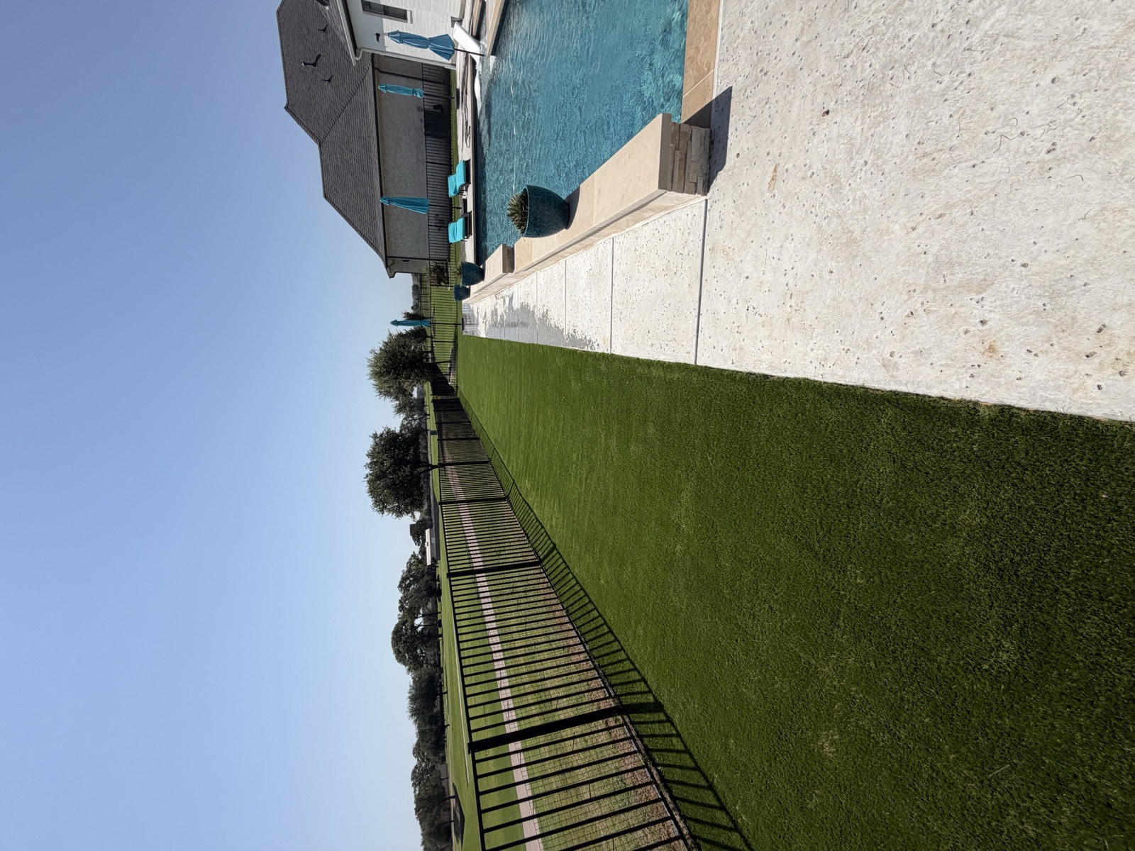 Artificial turf laid beside a stone paver patio